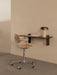 Angled view of the dark wood Corbel Desk mounted on a beige wall, with a light wood Co Task Chair and a Reverse Table Lamp.