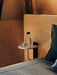 Corbel Shelf in white marble, mounted on a wooden headboard, functioning as a minimalist bedside table with a water bottle.