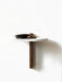 A wall-mounted Corbel Shelf with a round white marble top and a dark wood bracket, holding a black wallet and smartphone.