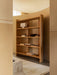 The Crescent Shelving H173 in oak, styled with a Nonna Lamp, Rond Bowl, and books, in a room with a marble Plinth Low table.