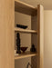 Close-up of Audo Crescent Shelving in light oak, styled with a dark wood sculpture, ceramic vases, and decorative bowls.
