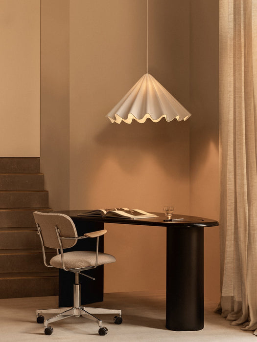 A white Dancing Pendant Lamp hangs over a black Eclipse Desk and a Co Task Chair in a warmly lit office with beige walls.