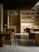 The white Dancing Pendant Lamp hangs in a softly lit restaurant, surrounded by wooden dining tables and chairs.