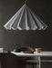 The grey, pleated Dancing Pendant Lamp illuminates a dining setting with Harbour Chairs, a black teapot, and a Split Tray.