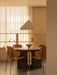 The Dancing Pendant lamp hangs over an Androgyne Dining Table with a Taper Bowl, and Penguin Dining Chairs in a sunlit room.