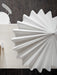 A close-up, overhead shot of the white, pleated Dancing Pendant Lamp, showing its textured surface and wavy, star-like edges.