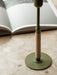 A close-up of the olive green Duca Candle Holder with its textured rattan-wrapped stem, placed on a marble surface.