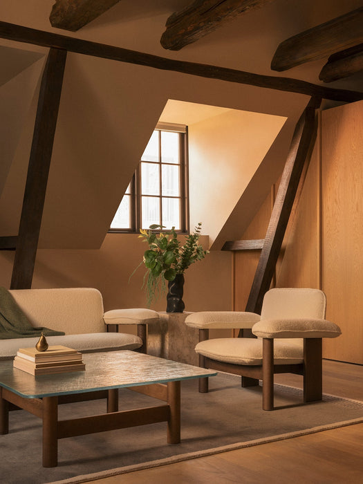 Brasilia Sofa and Low Back Lounge Chair in an attic room with a glass coffee table and Duomo Rug under exposed wood beams.