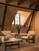 Brasilia Sofa and Low Back Lounge Chair in an attic room with a glass coffee table and Duomo Rug under exposed wood beams.