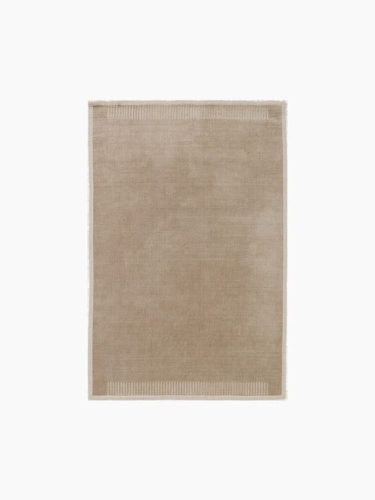 A top-down view of the rectangular Duomo Rug in Limestone Beige, showing a solid-coloured body and decorative ribbed borders.