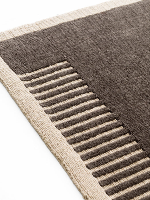 A close-up of the Duomo Rug in Marble Grey, showcasing its woven texture with a beige border and a raised, striped pattern.