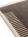 A close-up of the Duomo Rug in Marble Grey, showcasing its woven texture with a beige border and a raised, striped pattern.