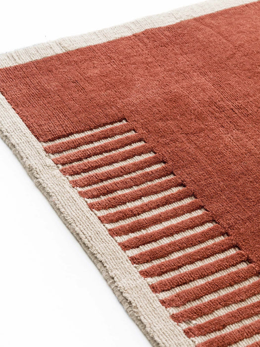 A close-up of the Duomo Rug in Terracotta Red, showing its woven texture, beige border, and pattern of raised stripes.