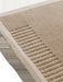 A detailed corner view of the Duomo Rug in Limestone Beige, showing its soft pile, woven border, and raised ribbed pattern.