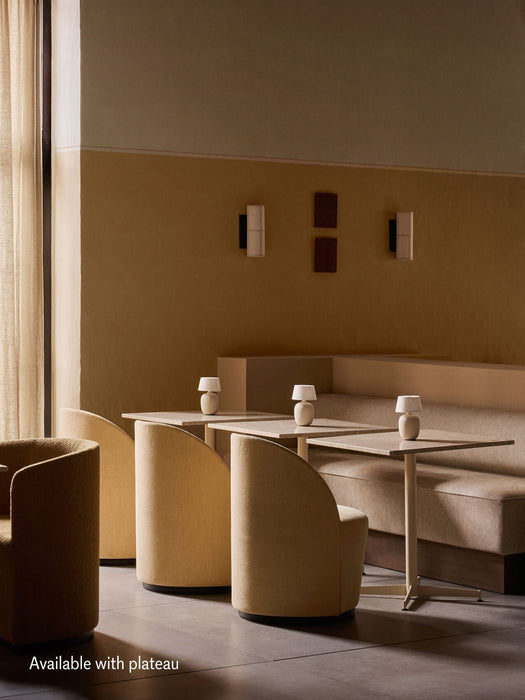 A sunlit restaurant with the Eave Dining Sofa corner banquette in beige, featuring a plateau back, tables, and chairs.