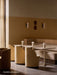 A sunlit restaurant with the Eave Dining Sofa corner banquette in beige, featuring a plateau back, tables, and chairs.