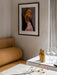 A corner setting with a mustard-yellow Eave Dining Sofa, a table set for dining, and a framed photograph on a light wall.