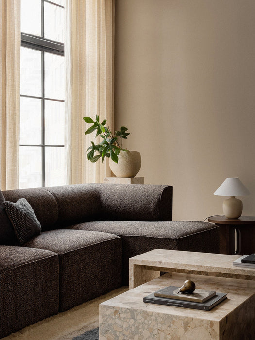 The dark Eave Modular Sofa with Chaise Longue in a corner, styled with marble Plinth coffee tables and a Plantas Planter.