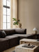 The dark Eave Modular Sofa with Chaise Longue in a corner, styled with marble Plinth coffee tables and a Plantas Planter.