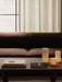 Three glowing Ignus Flameless Candles and books on a dark wood Jager Lounge Table in front of a brown Eave Modular Sofa.