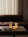 A dark wood Jager Lounge Table with three lit Ignus Flameless Candles, styled in front of a brown Eave Modular Sofa.