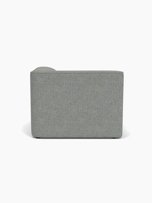Back view of the Eave Modular Sofa, 96, Chaise Longue upholstered in light grey Safire 12 fabric against a white background.