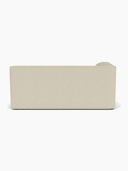 A back view of the light beige Eave Modular Sofa, 96, Corner 192, showcasing its straight silhouette and textured fabric.