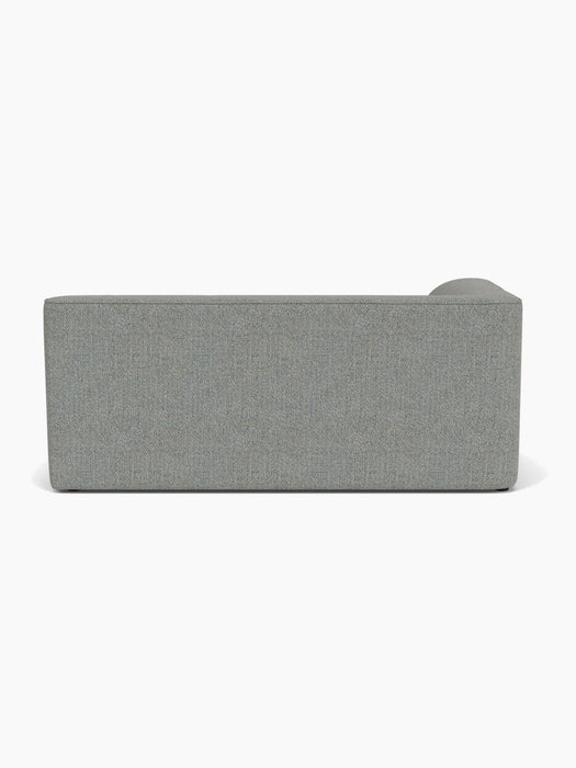 A back view of the Eave Modular Sofa, 96, Corner 192, upholstered in a textured grey Safire fabric against a white backdrop.