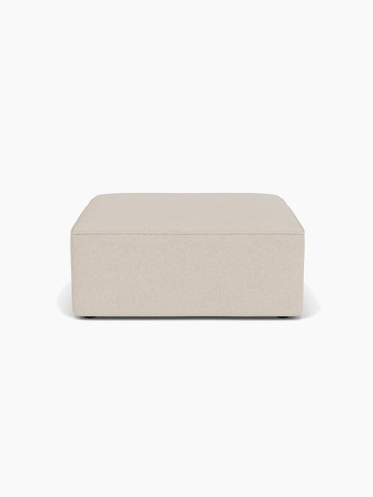 Front view of the Eave Modular Sofa Pouf, 96. The rectangular ottoman has light beige, textured upholstery.