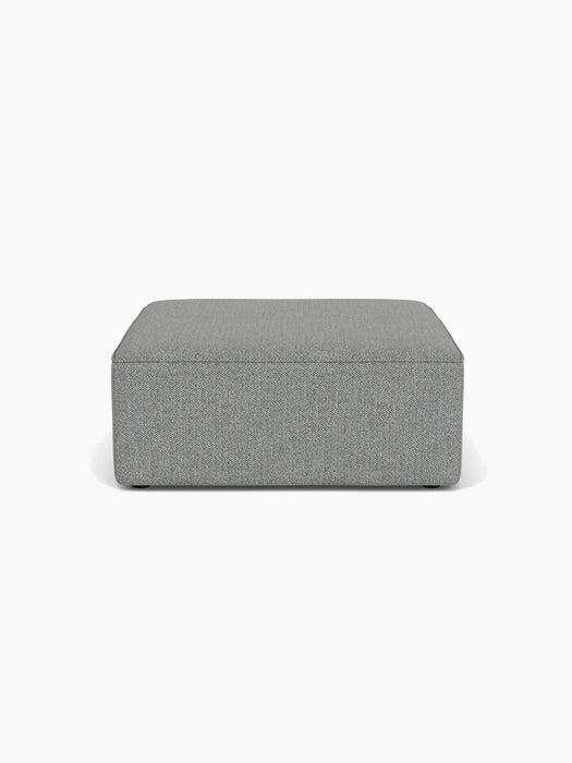 A front-on view of the rectangular Eave Modular Sofa Pouf, upholstered in a textured, grey-blue Safire fabric.