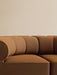 A close-up of the brown Eave Seamline Modular Sofa, highlighting the curved, padded sections of its concave corner backrest.