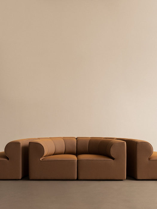 The Eave Seamline Modular Sofa, 86, Concave, Corner in a tan fabric, shown from the front against a simple, beige background.