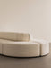 A close-up of the Eave Seamline Modular Sofa corner piece showcasing its curved form and textured, cream-coloured upholstery.