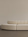 A close-up of the Eave Seamline Modular Sofa in cream bouclé, with its curved form and detailed backrest stitching.