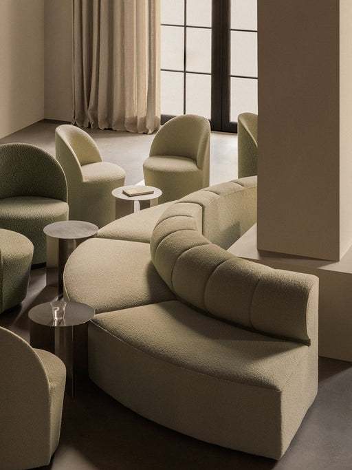A lounge setting with a curved, beige Eave Seamline Modular Sofa, Tearoom Side Chairs and Androgyne Side Tables.
