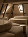 The cream Eave Seamline Modular Sofa and Androgyne Side Table in a warmly lit attic room with exposed dark wooden beams.
