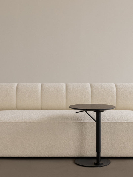 A close-up of the textured, off-white Eave Seamline Modular Sofa next to a slim, black Branch Side Table.