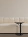 A close-up of the textured, off-white Eave Seamline Modular Sofa next to a slim, black Branch Side Table.