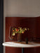 A close-up of the Hasse Vases and Bowl on a marble Column Table. Vases hold poppies in front of a reddish-brown wood panel.