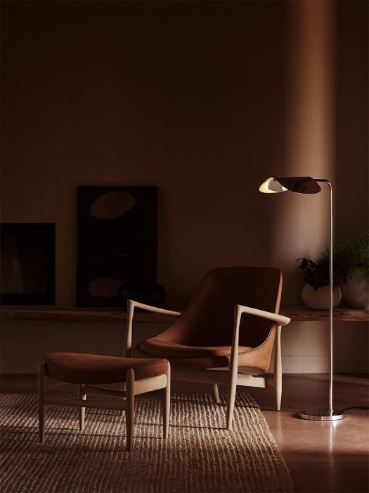 Elizabeth Lounge Chair and Ottoman in cognac leather and oak, styled on a woven rug beside a Wing Floor Lamp in a cosy room.