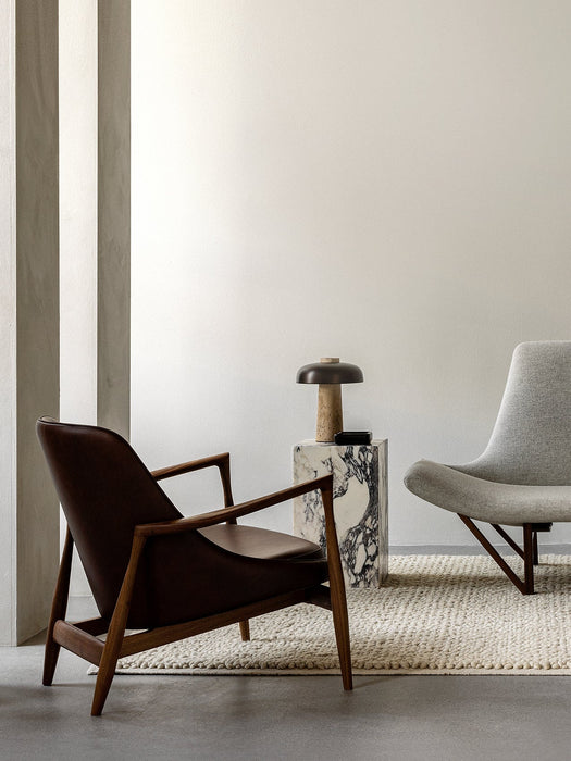 A living room featuring the brown leather Elizabeth Lounge Chair, a Plinth Tall marble table with a Reverse Table Lamp.