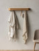 The wooden Epoch Rack mounted on a wall with a striped bathrobe, brush, and linen towel. A Harbour Chair is beside it.