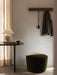 A Torso Table Lamp on an Eclipse Desk, a green Cairn Pouf, and an Epoch Rack on the wall in a softly lit room corner.