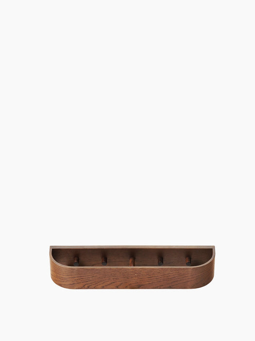 Front view of the Epoch Rack 50 in dark stained oak, a wall-mounted shelf with a curved front and five pegs inside.