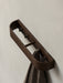 Angled view of the dark wood Epoch Rack, a modern wall rack with pegs, holding a brown woven towel against a light-grey wall.