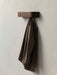 A minimalist dark oak Epoch Rack mounted on a light-coloured wall, with a brown textured blazer jacket hanging from it.