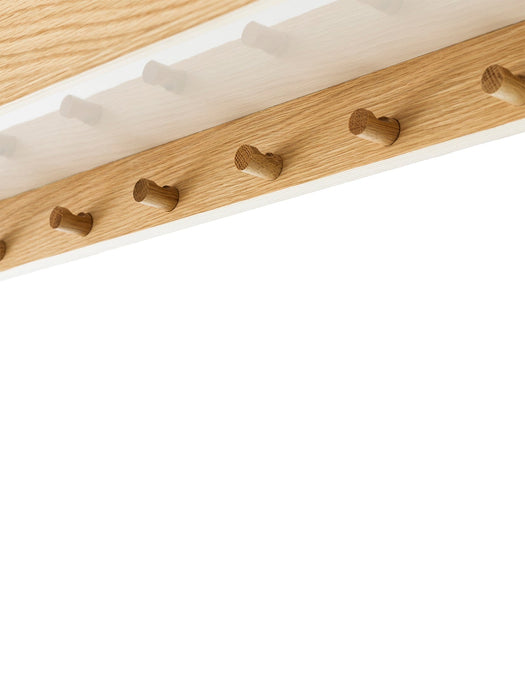 A close-up detail shot of the wooden hooks on a light oak shelf, viewed from below against a clean white background.