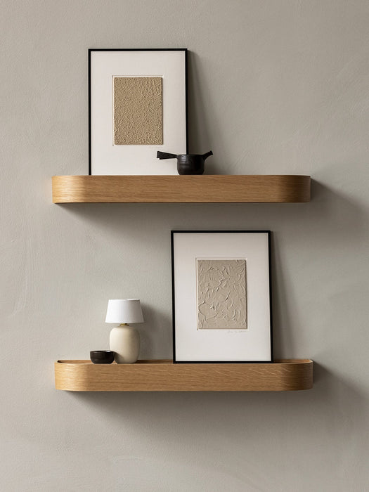 Two light oak Epoch Shelves against a grey wall. The bottom shelf holds a Torso Portable Table Lamp, NNDW Cup next to art.
