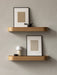 Two light oak Epoch Shelves against a grey wall. The bottom shelf holds a Torso Portable Table Lamp, NNDW Cup next to art.