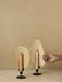A hand lights a candle in a black Flambeau Candle Holder with a brass reflector. An identical holder sits beside it.